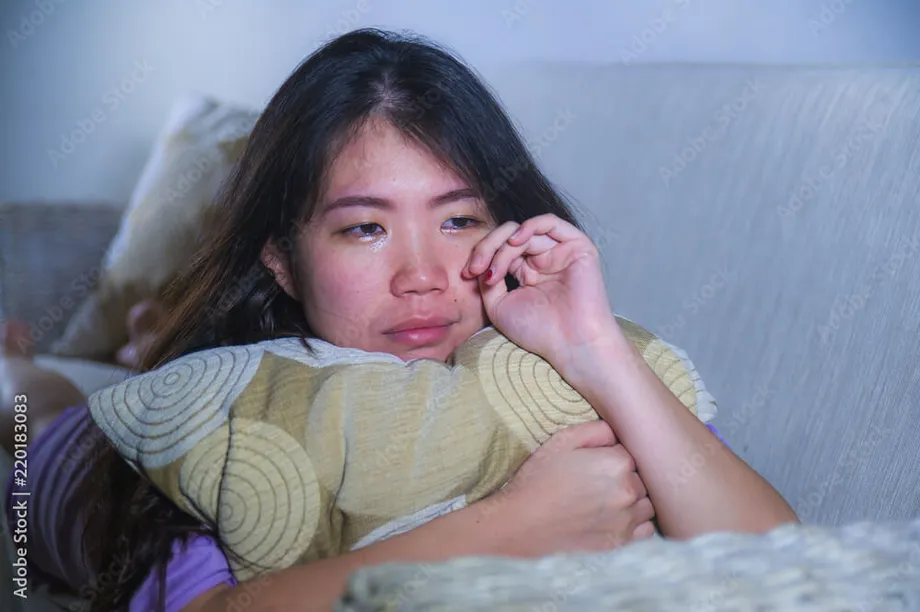 young sad and depressed Asian Korean woman at home sofa couch crying ...
